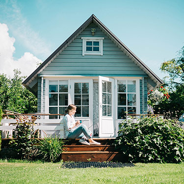 lady sitting in front of small house